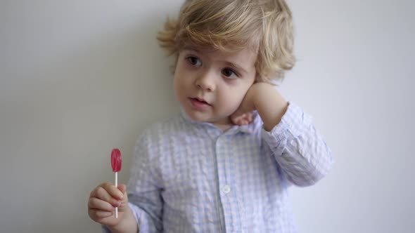 Cute boy enjoying sweet lollipop alt