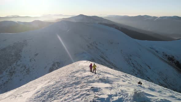 Drone Following Adventurous Couple Descending a Snow Slope