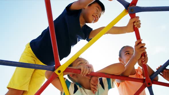 Schoolkids playing on dome climber in playground alt