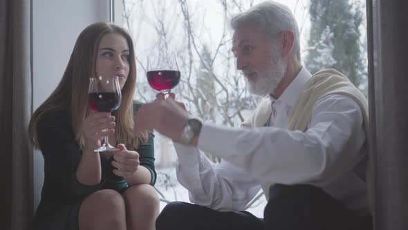 Confident Senior Caucasian Man Talking About Wine with Young Pretty Woman. Grey-haired Male Retiree alt