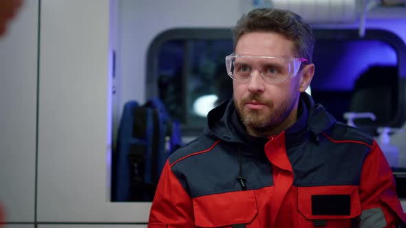 Serious Paramedic Ambulance Talking with Colleague in Ambulance Car alt