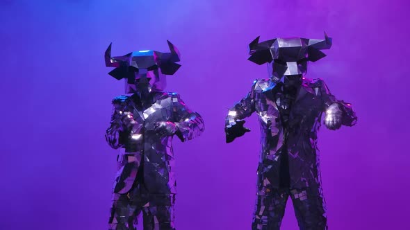 Two Shiny Bulls in Costumes Made of Mirrors Fun Dancing on Neon Blue Pink Studio Background alt