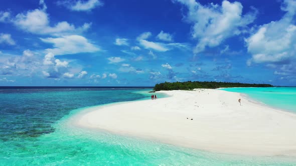 Young girls walking along the sandbar in the tropical ocean. Aerial. Empty white beach in Maldives alt
