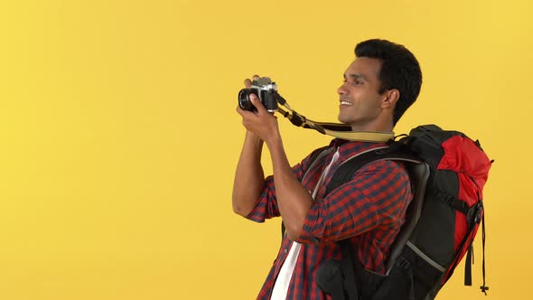 Portrait of a smiling young indian tourist backpacker enjoying taking photos