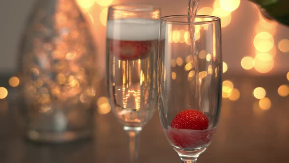 Champagne is Poured Into Wineglasses with Ripe Strawberries