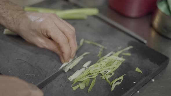 Closeup of Male Chef’s Hands Slicing Vegetables on Cutting Board alt