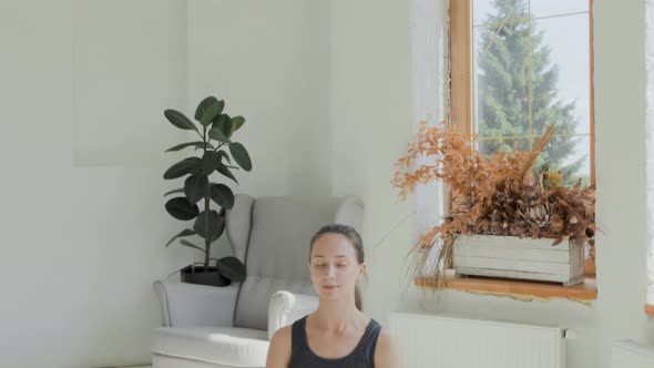 Young Fit Brunette Girl Wearing Sportswear Sits in Lotus Pose Meditating at Home