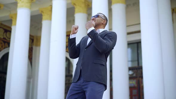 Successful Excited African American Businessman Making Victory Gesture Standing Outdoors alt