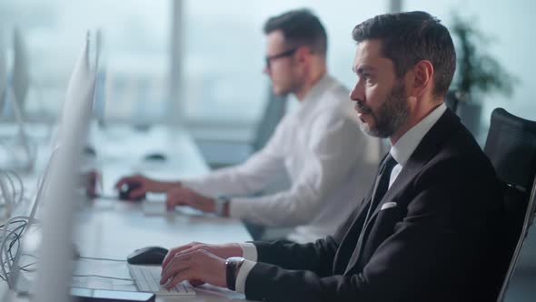 Portrait of Adult Entrepreneur in Open Space Office Working on Decktop Computer alt