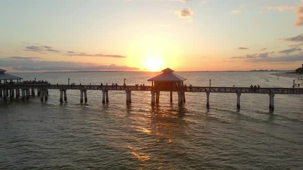 People looking to a beautiful sunset over the ocean in Fort Myers Pier, Florida alt