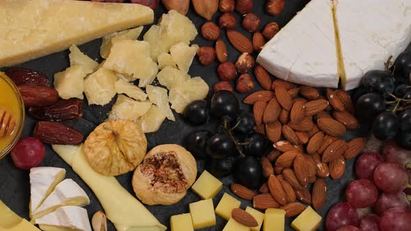 Cheese plate with hard cheeses camembert, brie, parmesan, dutch cheese, grapes, fruit, honey, nuts alt