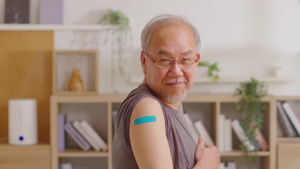 Happy Asian Elderly man received anti virus vaccine cheerful thumbs up with bandage,Senior handsome alt
