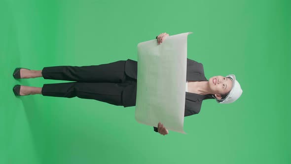 Full Body Of Asian Female Engineer Looking At Blueprint In The Green Screen Studio alt