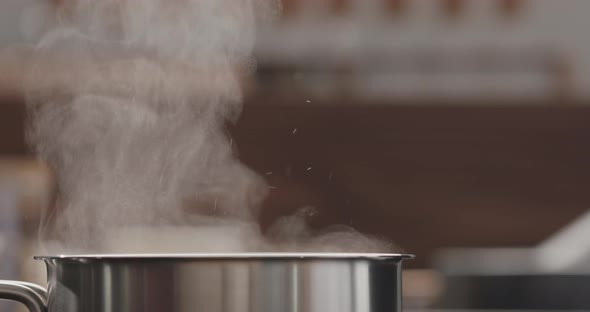 Slow Motion Man Adding Salt to Boiling Water in Saucepan