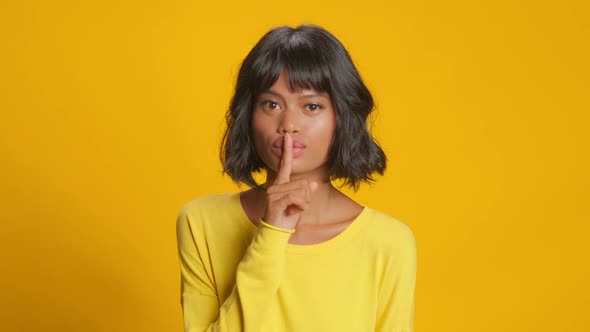 Mysterious Dark Skinned Woman Presses Index Finger To Lips Makes Silence Gesture alt