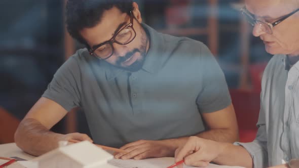 Mixed-Aged Diverse Male Architects Working Together on Construction Plan alt