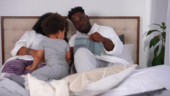 Relaxed African American Family Lying in Bed in the Morning Reading alt