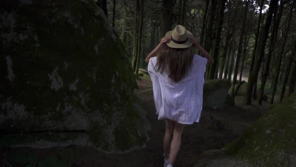 Lady traveler running in wonderland magic forest with huge stones, tall green trees, lianas. Wonder.