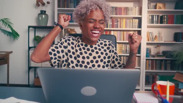 Excited African Woman Winner Looks at Laptop Celebrates Success at Home Office alt