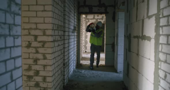 Builder Carrying Pipes Inside Unfinished Building alt