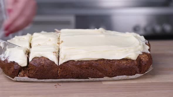 Cutting Freshly Baked Carrot Cake With White Cream Cheese Frosting On Top. close up, slider right alt