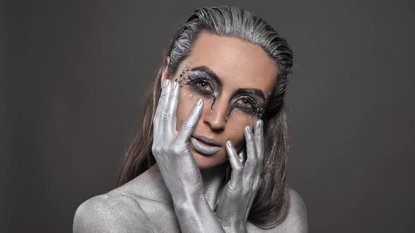 Portrait of a Beautiful Woman with Silver Paint on Her Skin and Hair