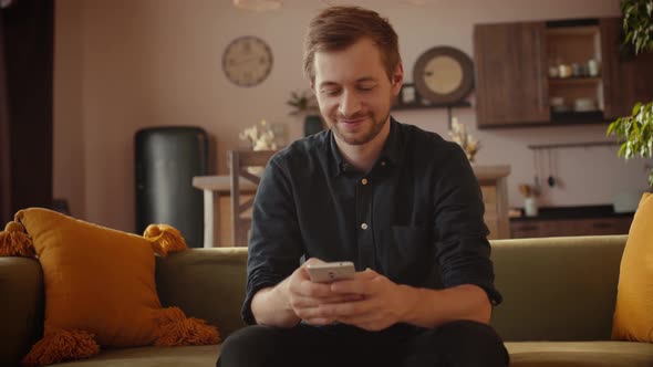 Young Man Scrolling Through His Smartphone at Home