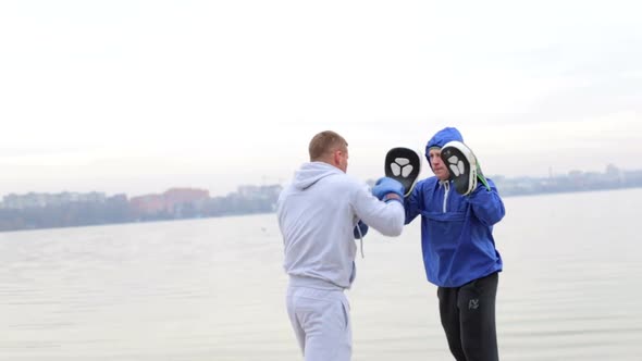 A young fighter in a gray suit runs with dumbbells in his hands and waving his arms alt