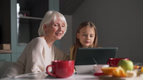Granddaughter watching something on tablet with grandmother alt