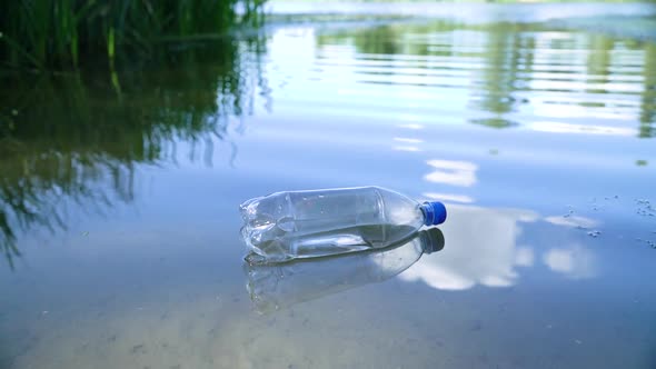 Transparent Plastic Bottle Floats Near the Shore in the River alt