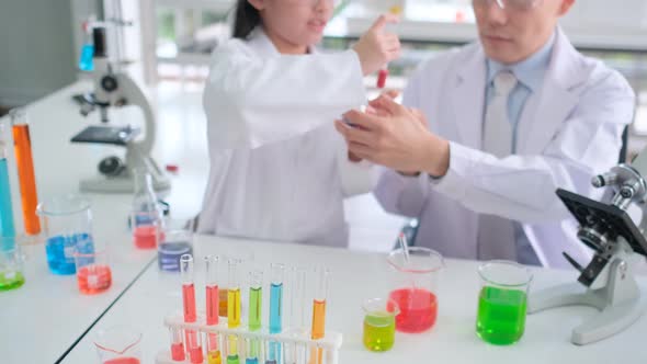 Teacher teach young scientist  junior or kids girl to learn using dropper or short pipette to mix alt