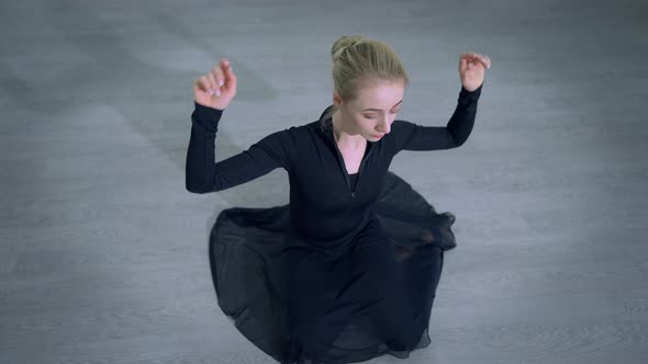 Top View Blond Caucasian Ballerina with Blue Eyes Sitting on Floor Adjusting Hairstyle and Looking alt