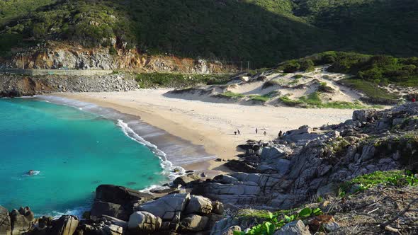 Wide angle of Thung Beach Bãi Chuối banana point people cleaning beach which is heavily polluted alt