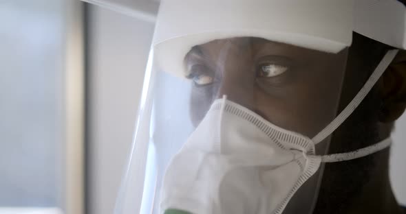 Close Up Portrait of African Doctor Wearing Respiratory Mask and Face Shield in Hospital alt