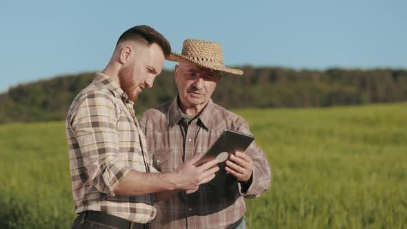 A Man is Showing an Old Farmer Information on a Tablet alt