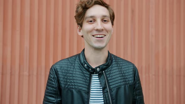 Portrait of Goodlooking Young Man Making Eyes and Smiling Looking at Camera Outdoors alt