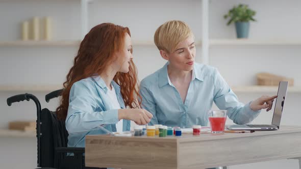 Little Redhead Handicapped Girl Exercising with Mother at Home Watching Video Tutorial on Laptop and alt