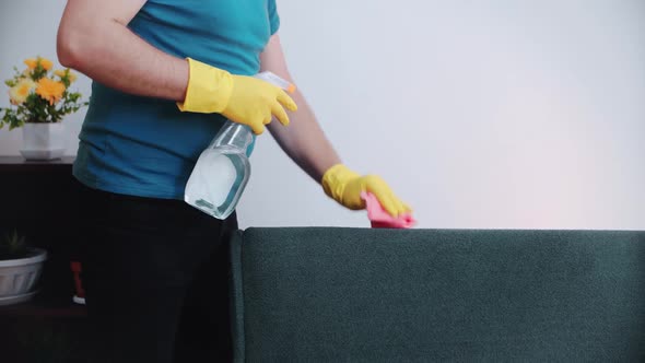 Cleaning concept. A man cleans the sofa in the room