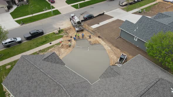 Concrete crew working together to finish long new driveway in residential neighborhood.