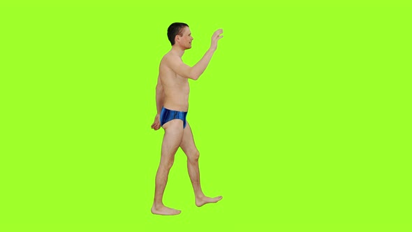Young Man in Swim Trunks Waving Greetings While Walking