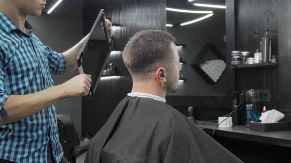 Barber Holding a Mirror for His Male Client To Check Out New Haircut