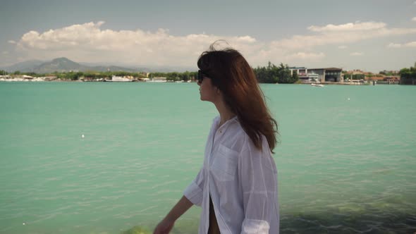 Real Time Portrait Shot of a Young Beautiful Girl Walking Along the Embankment of Lake Garda