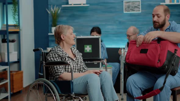 Man Nurse Putting Oximeter on Hand of Elder Invalid Woman alt