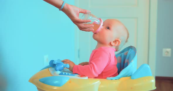 Mom's Hand Holds a Bottle of Water or Juice Baby Drinks alt