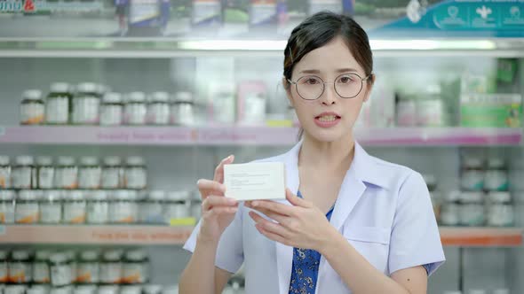 Asian female pharmacist explaining the medicinal properties on the pillbox to a patient or customer