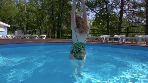 Sexual Blonde Woman Is Standing in Swimming Pool, Whirling and Flirting with Camera in a Sunny Day