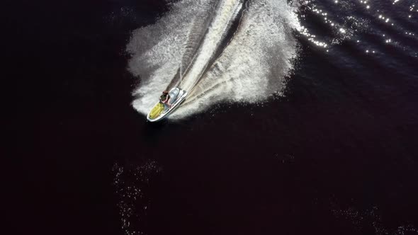 Mom and Daughter Ride Along the River on a Personal Watercraft. Aerial View alt