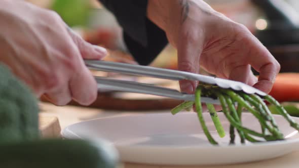 Cook Serving Roasted Asparagus on Plate alt