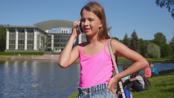 Portrait of Preteen Schoolgirl Talk on Mobile Phone Standing in School Park by Tommy_Envato 