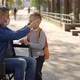 Close Up of the Disabled Father in Mask Sitting on the Wheel Chair Wearing Mask to His Son Before - VideoHive Item for Sale